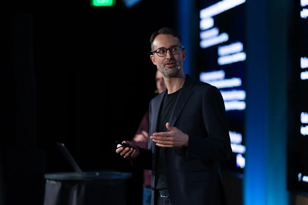 Kog CEO Gaël Delalleau speaking on stage while holding a presentation clicker.